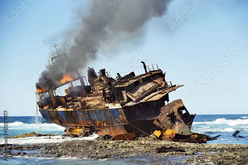 Stranded fish cutter lying burning at a reef.