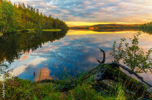 Sunset with colorful clouds over the lake in the autumn forest