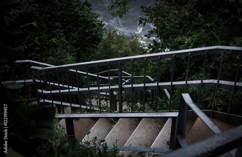 Rusty stairs followed from the forest to the coast photo