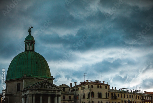 VENICE, ITALY - AUGUST 19, 2016: Colorful facades of old medieval buildings against dramatic storm clouds a day before occurred earthquakes in the country on August 19, 2016 in Venice, Italy. photo