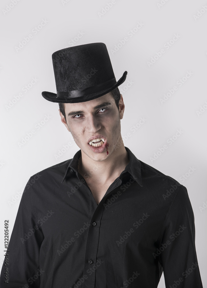 Portrait of a Young Vampire Man with High Hat and Black T-Shirt, Looking at the Camera, On Light Background. Portrait of a Young Vampire Man with High Hat and Black T-Shirt, Looking at the Camera, On Light Background.