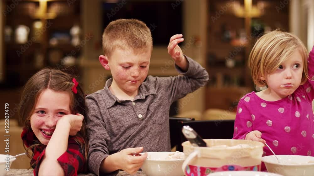Children at home eating ice cream and raising their hands into the air Children at home eating ice cream and raising their hands into the air