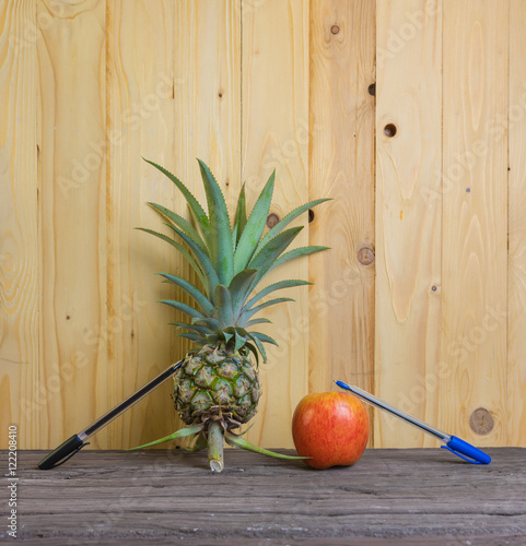 Pen-Pineapple-Apple-Pen on wooden background. photo