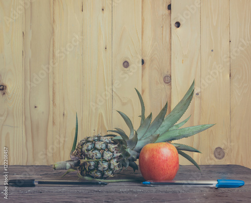 Pen-Pineapple-Apple-Pen on wooden background. photo