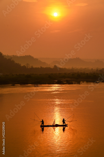 The silluate fisherman casting a net into the water on during sunset,Thailand