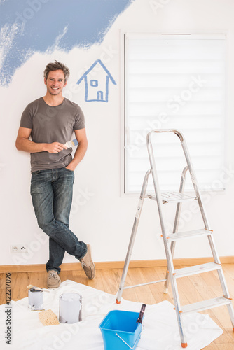 Handsome man painting the indoors walls of his new home