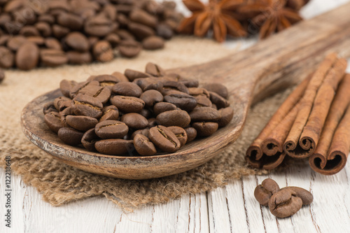 Coffee beans in a wooden spoon on old wooden table.