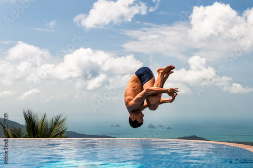 Young athletic man jumps into the pool at the top of the mountain
