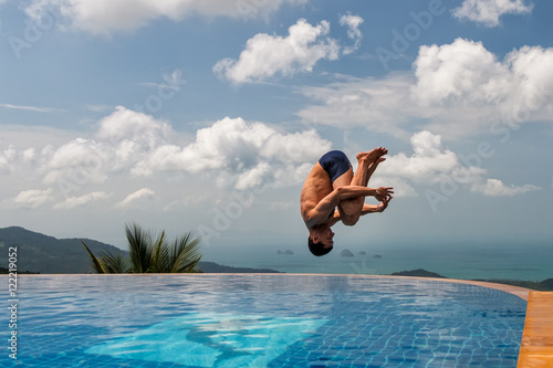 Young athletic man jumps into the pool at the top of the mountain

