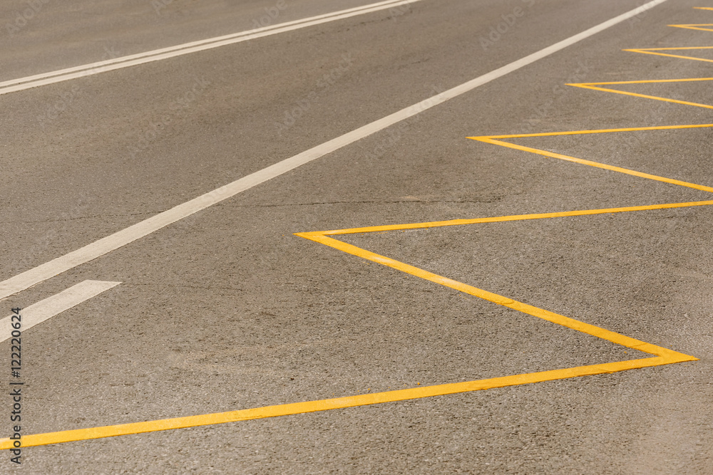 Gray asphalt surface with yellow and white stripes, texture, background Gray asphalt surface with yellow and white stripes, texture, background