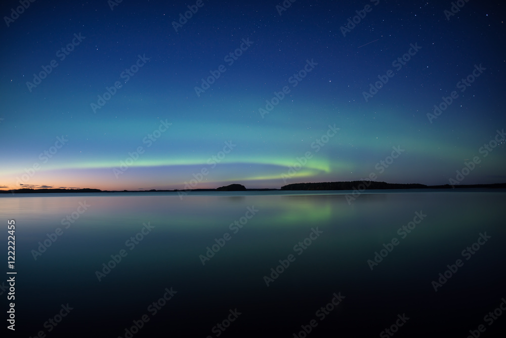 Fototapeta premium Northern lights dancing over calm lake in Sweden