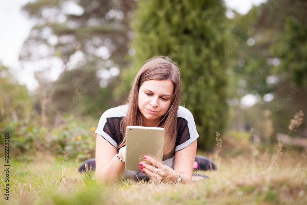 Young teenage girl using tablet outdoor; looking concentrated an