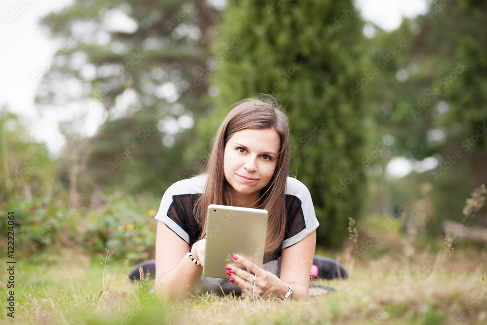 Pretty young brunette girl relaxing and using tablet in outside Pretty young brunette girl relaxing and using tablet in outside