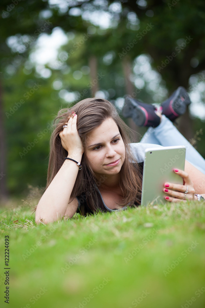 Pretty young brunette girl relaxing and using tablet in outside Pretty young brunette girl relaxing and using tablet in outside
