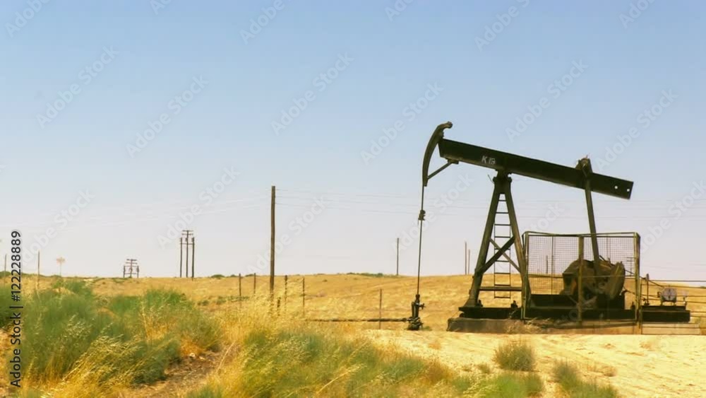 A stationary shot of an oil rig pumping oil in a field near Bakersfield, CA. A stationary shot of an oil rig pumping oil in a field near Bakersfield, CA.