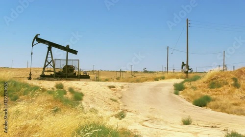 A stationary shot of an oil rig pumping oil in a field near Bakersfield, CA.