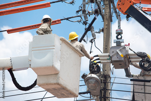 men working on a transformer on a electricity power pole in Thailand
