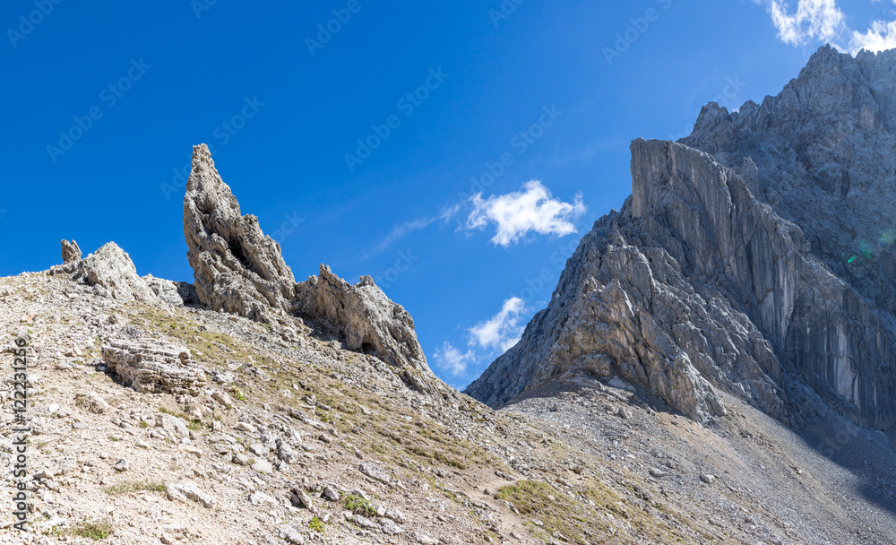 Alpenpass mit spitzen Felsen vor blauem Himmel
