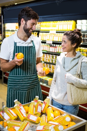 Smiling male staff assisting a woman with grocery shopping
