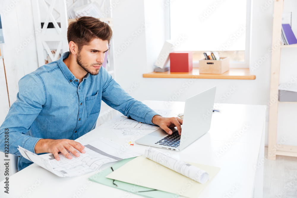 Handsome young smart businessman working with documents and computer