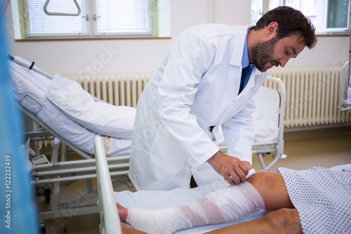 Canvas Print Doctor bandaging leg of patient