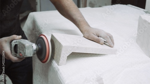 Worker polishes marble plate with tools