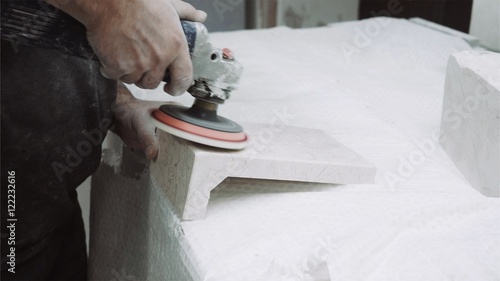 Worker polishes marble plate with tools