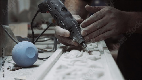 Engineer engraver working with tools on a marble ornament plate, close up