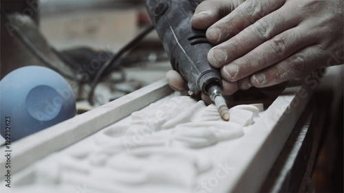 Engineer engraver working with tools on a marble ornament plate, close up
