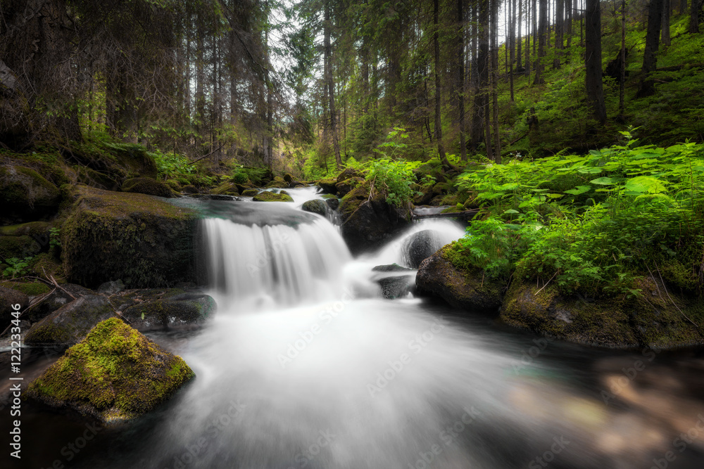 Amazing waterfall flowing between large rocks in a deep green forest at Low Tatras National park, Slovak Republic. Amazing waterfall flowing between large rocks in a deep green forest at Low Tatras National park, Slovak Republic.