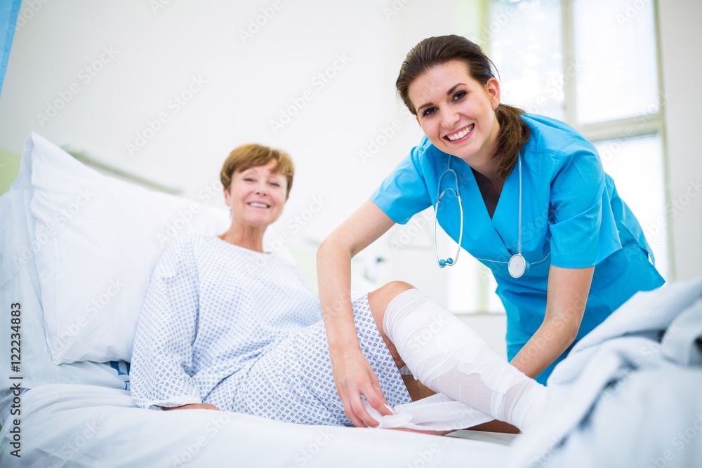 Nurse bandaging leg of patient Nurse bandaging leg of patient