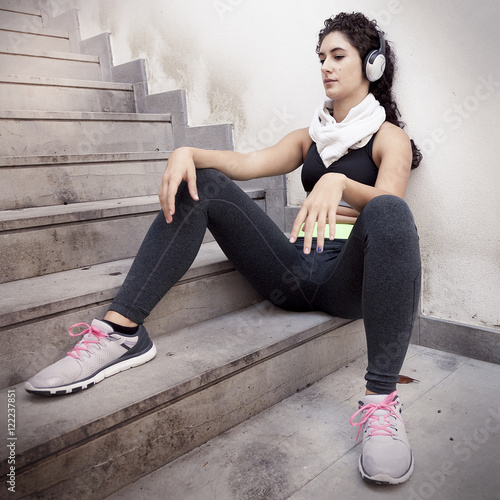 young female runner relaxing listening to music from headphones