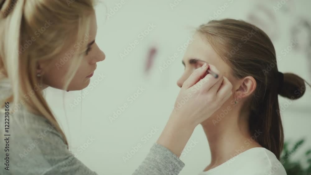 Make-up work. Make-up artist and model. Makeup Close-up face of a model. Make-up artist removes the extra shade on the model s eyelid. Make-up artist puts a brush for make-up and making feather. Make-up work. Make-up artist and model. Makeup Close-up face of a model. Make-up artist removes the extra shade on the model s eyelid. Make-up artist puts a brush for make-up and making feather.
