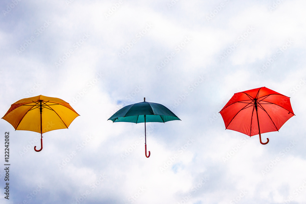Yellow Umbrella, Green Umbrella and Red Umbrella floating in the Air under Cloudy Sky