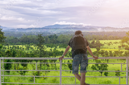 Backpacker standing on the balcony and look at forest and the mountain.