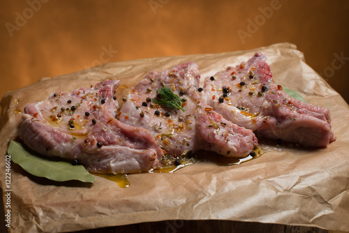 Raw pork ribs with spices, salt and rosemary on dark wooden background