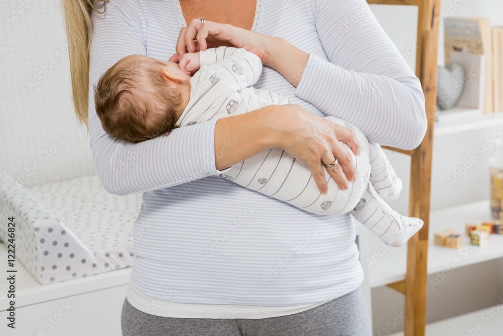 Fototapeta premium Mid-section of mother holding her baby boy