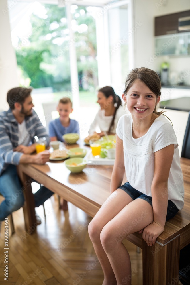 girl sitting on table while family having breakfast girl sitting on table while family having breakfast