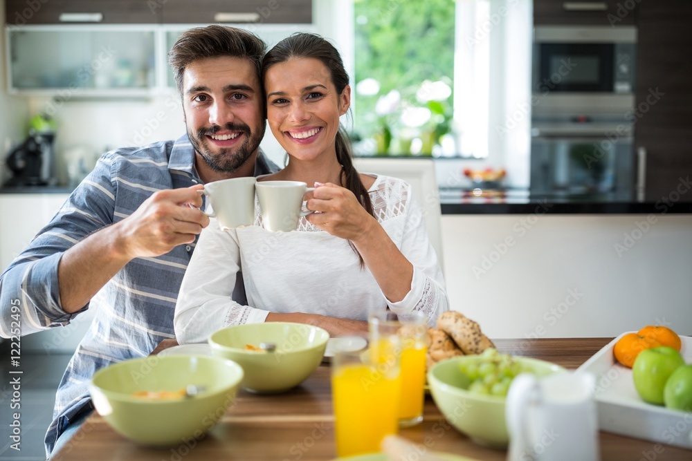 couple toasting a cup of coffee while having breakfast