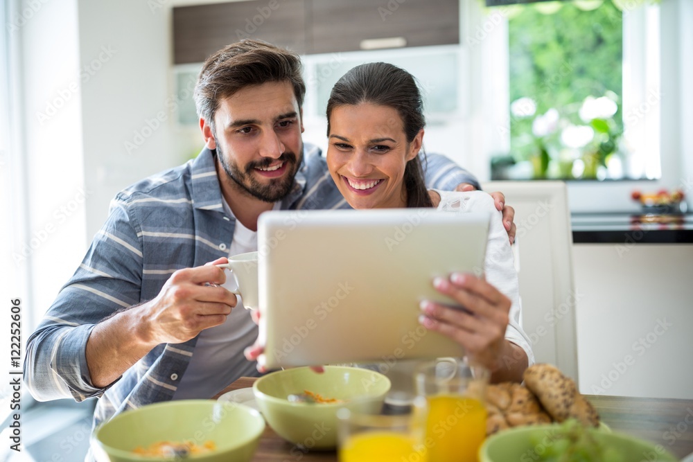 Couple using digital tablet while having breakfast Couple using digital tablet while having breakfast