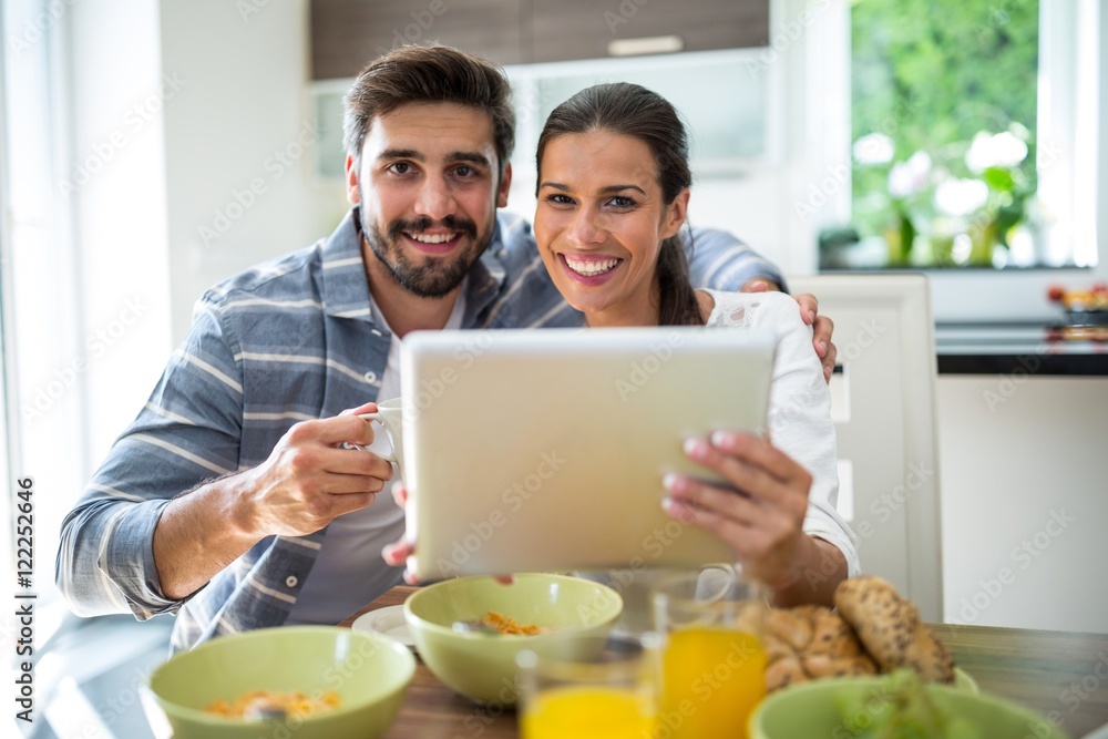 Couple using digital tablet while having breakfast at home Couple using digital tablet while having breakfast at home