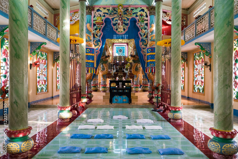 Interior of Buddhist temple with high columns and bright colorful walls. Pillows for pray are laying down on the floor before an Buddhist deity altar Interior of Buddhist temple with high columns and bright colorful walls. Pillows for pray are laying down on the floor before an Buddhist deity altar