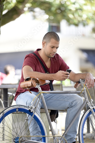 Man with bicycle sitting on park bench © goodluz