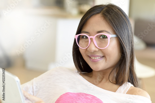 Young asian woman with pink eyeglasses using digital tablet