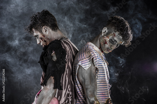 Two male zombies standing on black smoky background, head and shoulder shot