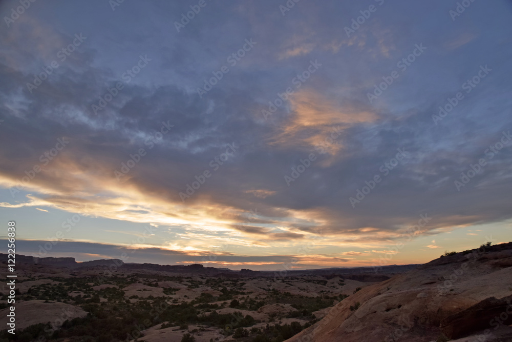 Desert sunset wide angle with clouds and brush and stone