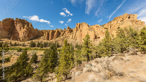 The sheer rock walls. Beautiful landscape of yellow sharp cliffs. Dry yellow grass grows at the foot of cliffs. Smith Rock state park, Oregon
