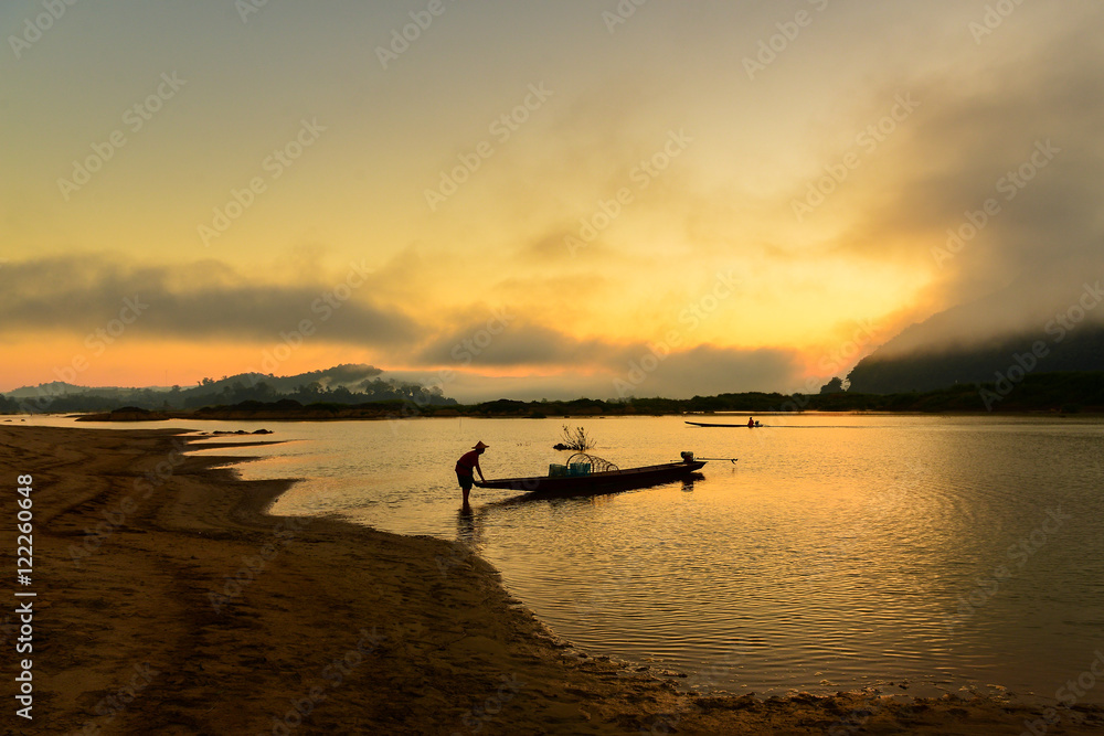 The silluate fisherman casting a net into the water on during sunset,Thailand The silluate fisherman casting a net into the water on during sunset,Thailand