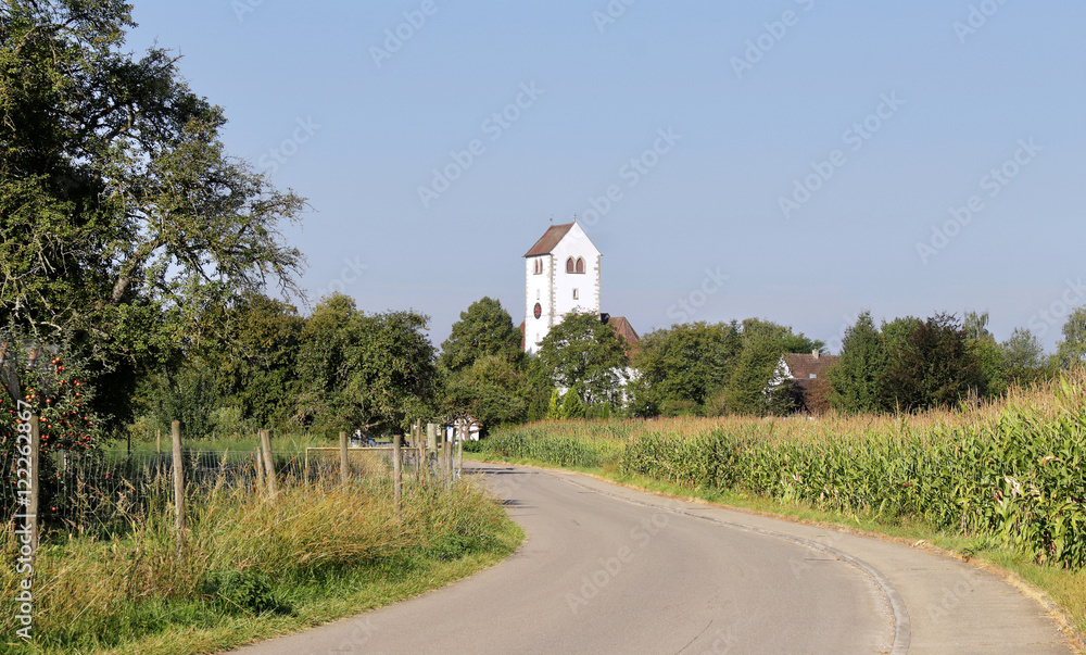Quiet country lane in Germany with white church tower