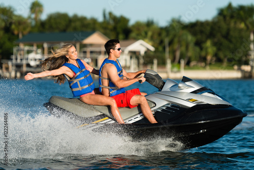 Attractive bikini swimwear couple cruising on personal water craft wetbike in Miami Beach Fort Lauderdale South Florida waterway photo